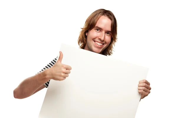 Sorridente giovane uomo con pollice in su tenendo vuoto bianco segno isolato su un whi — Foto Stock