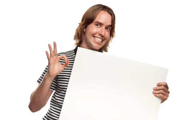 Весела молода людина зі знаком Окей тримає порожній білий знак ізольовано на білому B — стокове фото