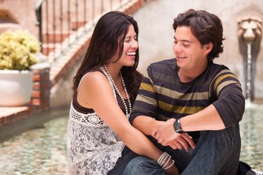 Attractive Hispanic Couple Ejoying Each Other At A Fountain. clipart