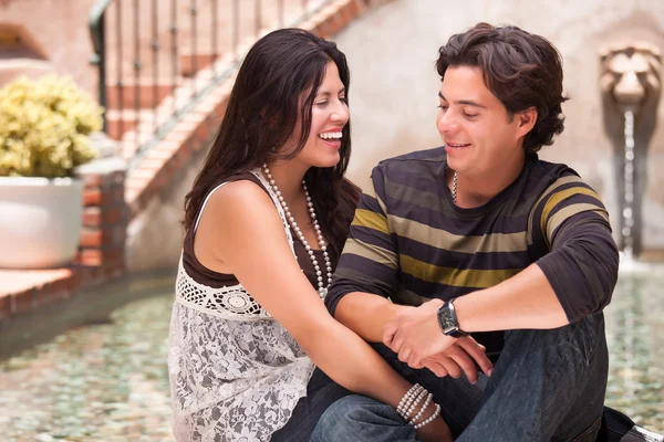 Attraktiva spansktalande par dock varandra på en fontän. — Stockfoto