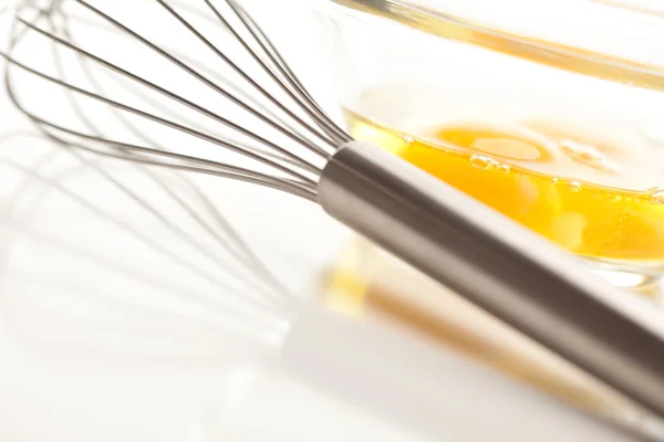 Handmixer met eieren in een glazen kom op een reflecterende witte achtergrond. — Stockfoto