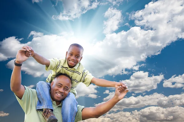 Çocuk üzerinde bulutlar ve gökyüzü ile mutlu bir Afrikalı-Amerikalı adam — Stok fotoğraf
