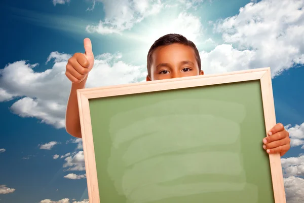 Trots latino jongen bedrijf leeg bord over hemel — Stockfoto