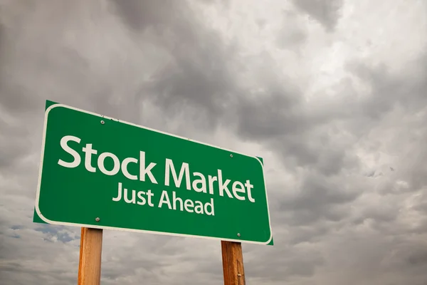 Akciový trh zelené dopravní značka nad bouřkové mraky — Stock fotografie