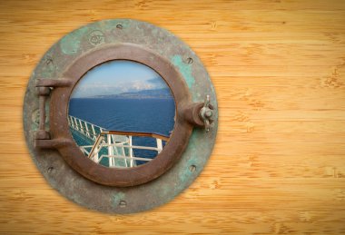 Antique Porthole on Bamboo Wall with View of Ship Deck Railing a clipart