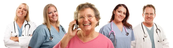 Mujer mayor feliz usando el teléfono celular y los médicos detrás —  Fotos de Stock