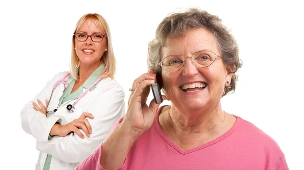 Старшая женщина использует мобильный телефон с женщиной-доктором позади — стоковое фото