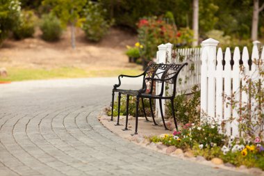 Iron Park Bench near a White Picket Fence clipart