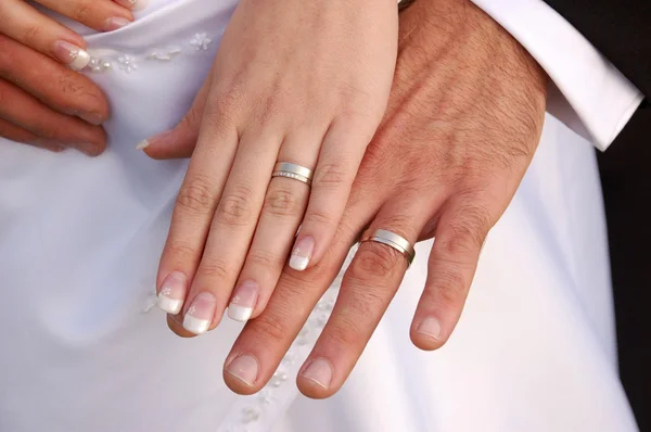 Bruden och brudgummen visar vigselringar Stockbild