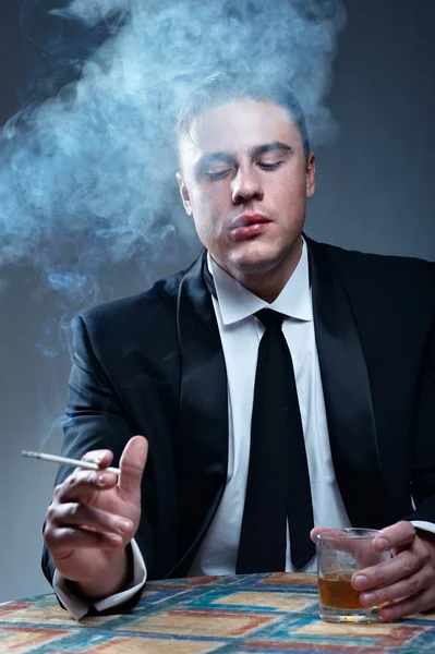 Porträtt av stilig rökning ung man med glas whiskey — Stockfoto