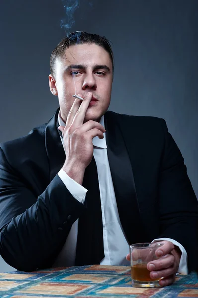 Πορτρέτο του καπνίσματος όμορφος νεαρός άνδρας με το ποτήρι ουίσκι — Φωτογραφία Αρχείου
