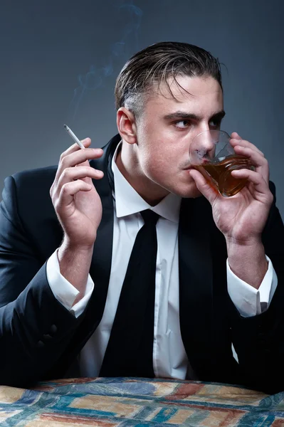Retrato de um homem de fato. Beber uísque e fumar — Fotografia de Stock