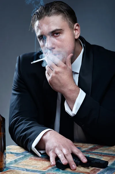 Portrait of handsome young mobster with smoking cigarette and gu — Stock Photo, Image