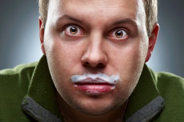 Closeup portrait of funny man. Yogurt traces on his lips clipart