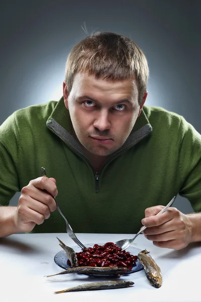 Porträt eines hungrigen Mannes. Bohnen und Fisch essen. — Stockfoto