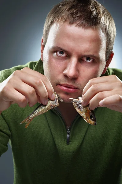 Homme corpulent affamé avec deux moitiés de poisson dans les mains — Photo
