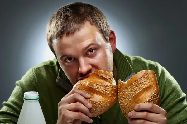 Hungriger Mann mit einem Mund voll Brot Stockbild