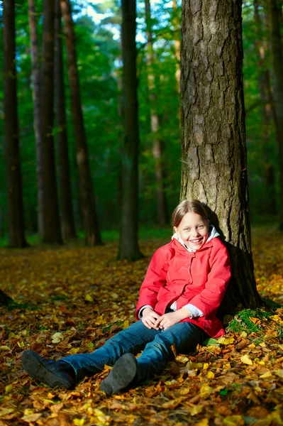 나무에 앉아 웃는 어린 소녀의 매력적인 초상화 — 스톡 사진