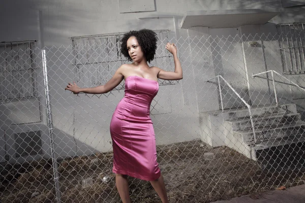 Woman posing by a fence — Stock Photo, Image