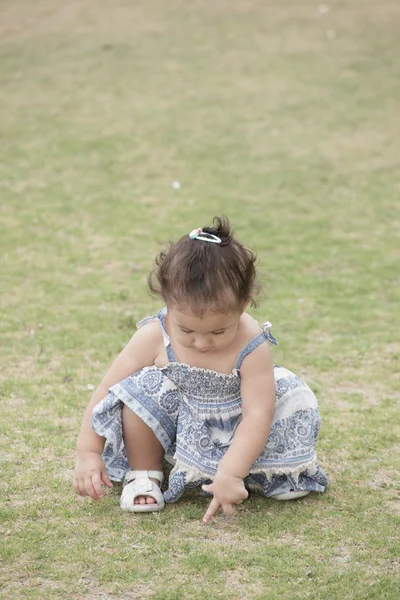 Malé dítě hraje s trávou v poli — Stock fotografie