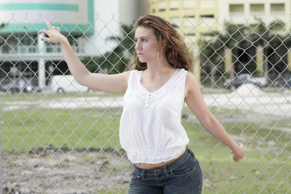 Woman by a chainlink fence — Stock Photo, Image