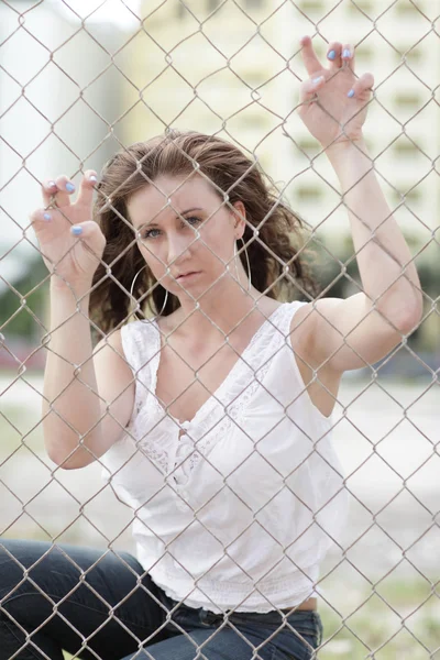 Vrouw poseren achter het hek — Stockfoto