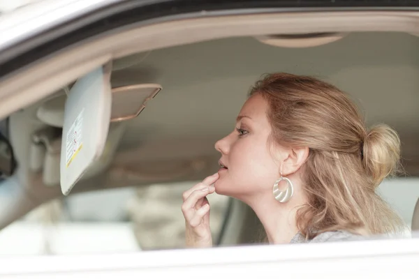 Feminino aplicando maquiagem em seu carro — Fotografia de Stock