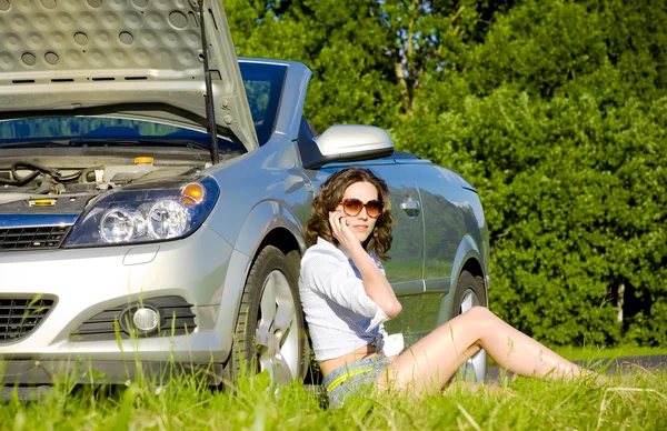 Yong woman is calling to service near broken car — Stock Photo, Image