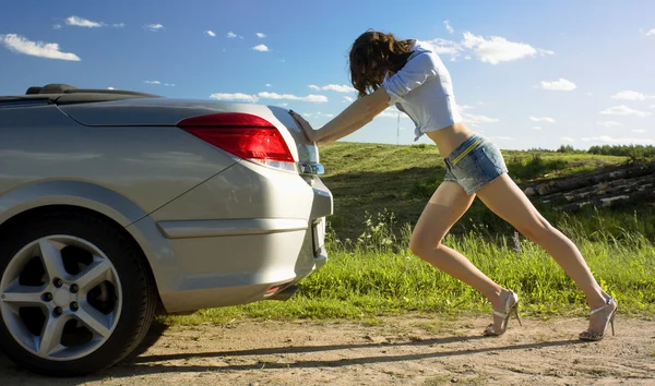 Mulher está empurrando carro quebrado — Fotografia de Stock
