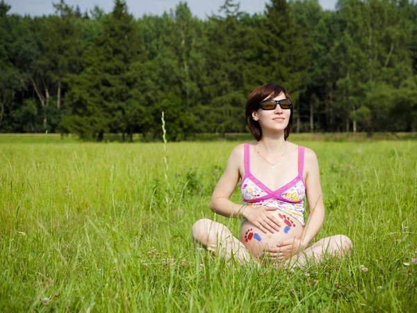 Embarazo mujer está sentado en una hierba — Foto de Stock