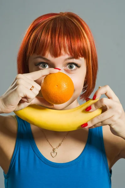 Κοκκινομάλλης κορίτσι με μπανάνα και πορτοκάλι — Φωτογραφία Αρχείου