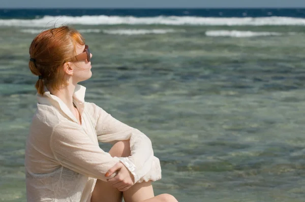 Красная женщина, отдыхающая у океана — стоковое фото