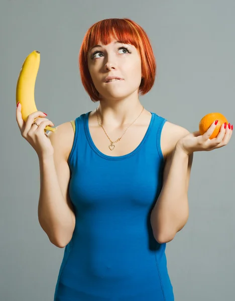 Menina de cabelos vermelhos com banana e laranja — Fotografia de Stock