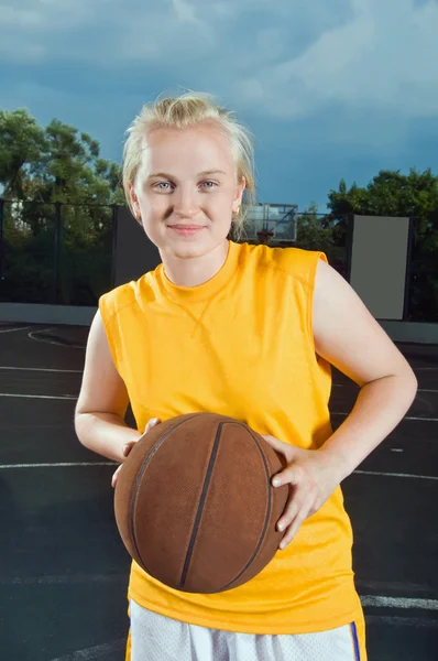 Весела підморгуюча дівчина-підліток з баскетболом — стокове фото
