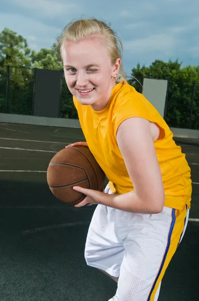 Cheerful winking teenage girl with basketball — Stock Photo, Image