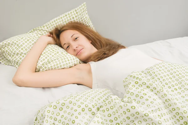 Beautiful young woman awake in bed — Stock Photo, Image
