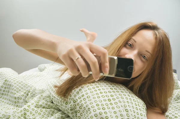 Žena v posteli s telefonem — Stock fotografie