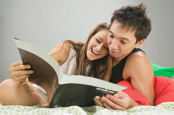 Happy couple reading a magazine — Stock Photo, Image