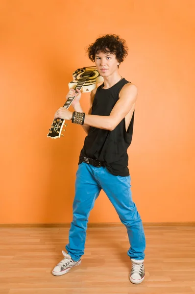 Молодой гитарист на ярком фоне — стоковое фото