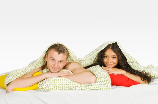 Casal escondido sob capas na cama — Fotografia de Stock