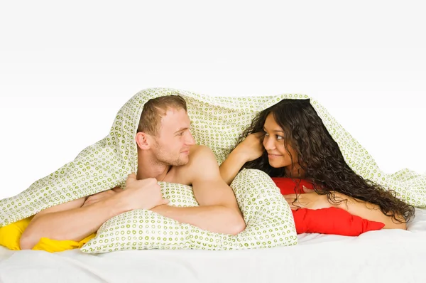 Casal escondido sob capas na cama — Fotografia de Stock