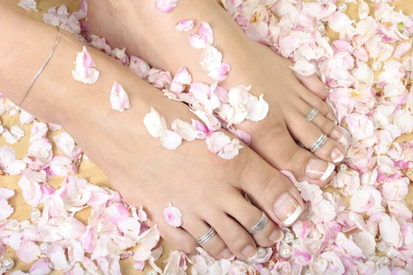 女人的脚和玫瑰花瓣 — 图库照片