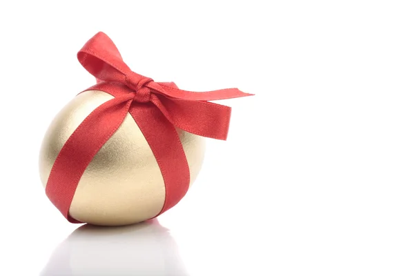 Złote jajko z czerwoną wstążką na biały — Zdjęcie stockowe