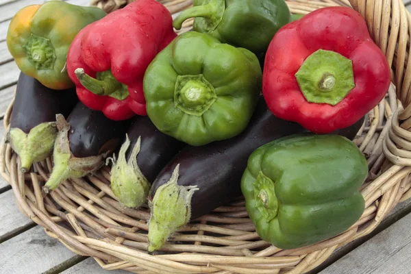 Ripe peppers and aubergine vegetables on willow basket — Stock Photo, Image
