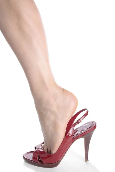 Kvinna fötter bär röda klackskor över vit bakgrund — Stockfoto