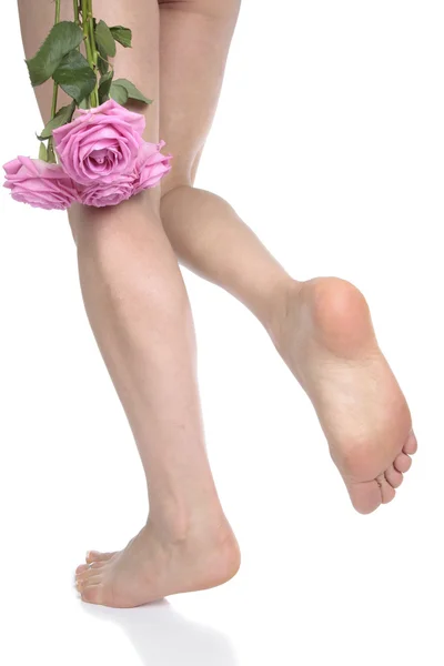 Vrouw voeten benen en bloemen op witte achtergrond — Stockfoto