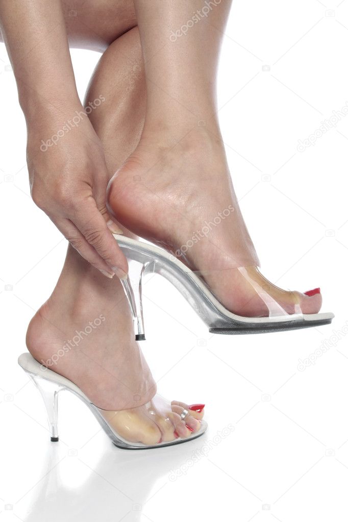Beautiful woman feet putting on heel shoes over white