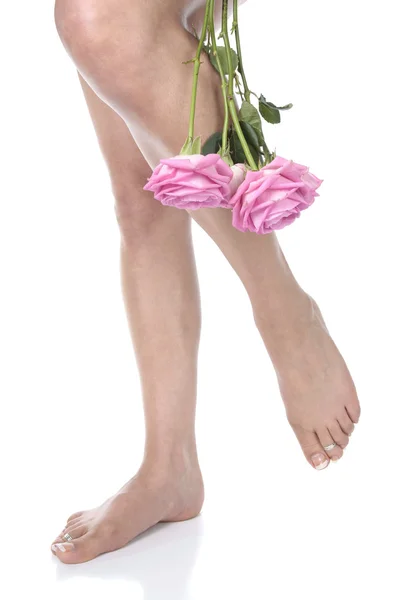 Kadın bacakları ve beyaz arka plan üzerinde çiçekler — Stok fotoğraf