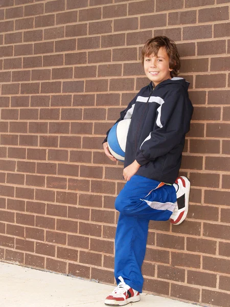 Ung pojke håller en basketboll — Stockfoto