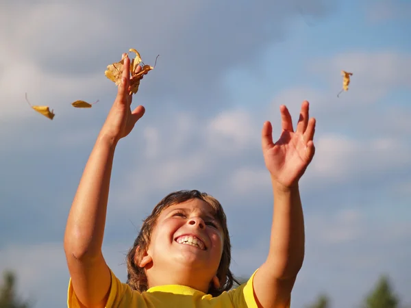 Jonge jongen bladeren gooien in de lucht — Stockfoto